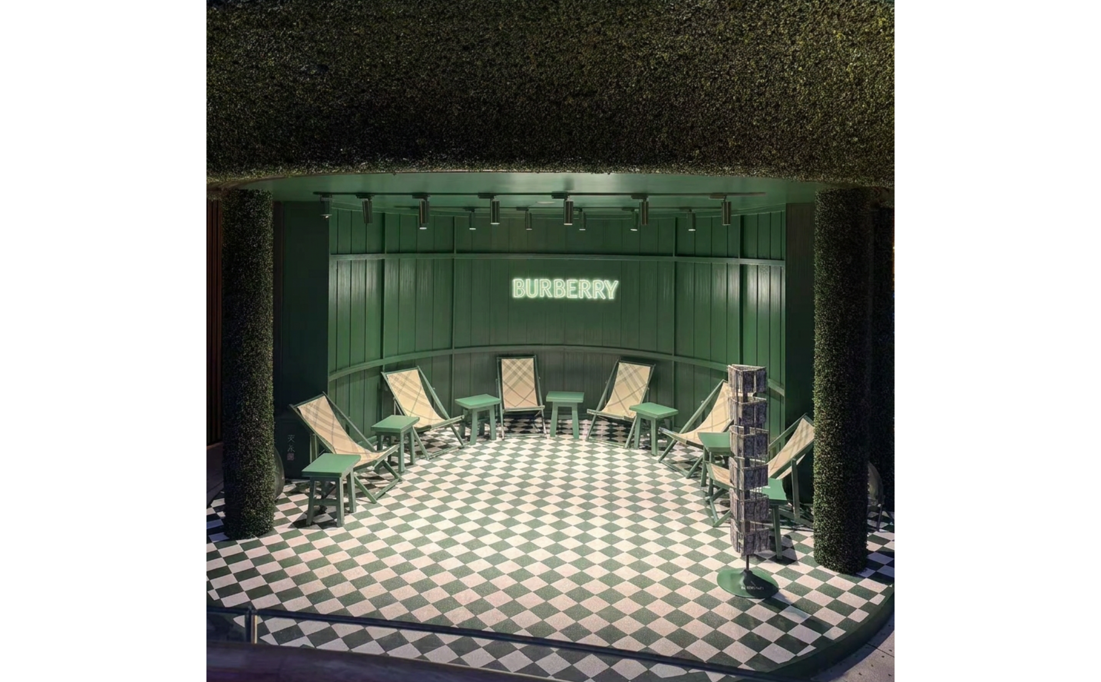 Burberry pop-up interior lounge with neon signage, checkered floor, and iconic check deck chairs